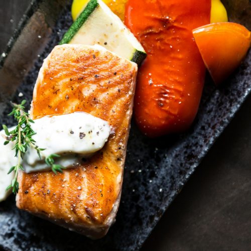 Delicious grilled salmon served with roasted vegetables and herb sauce.